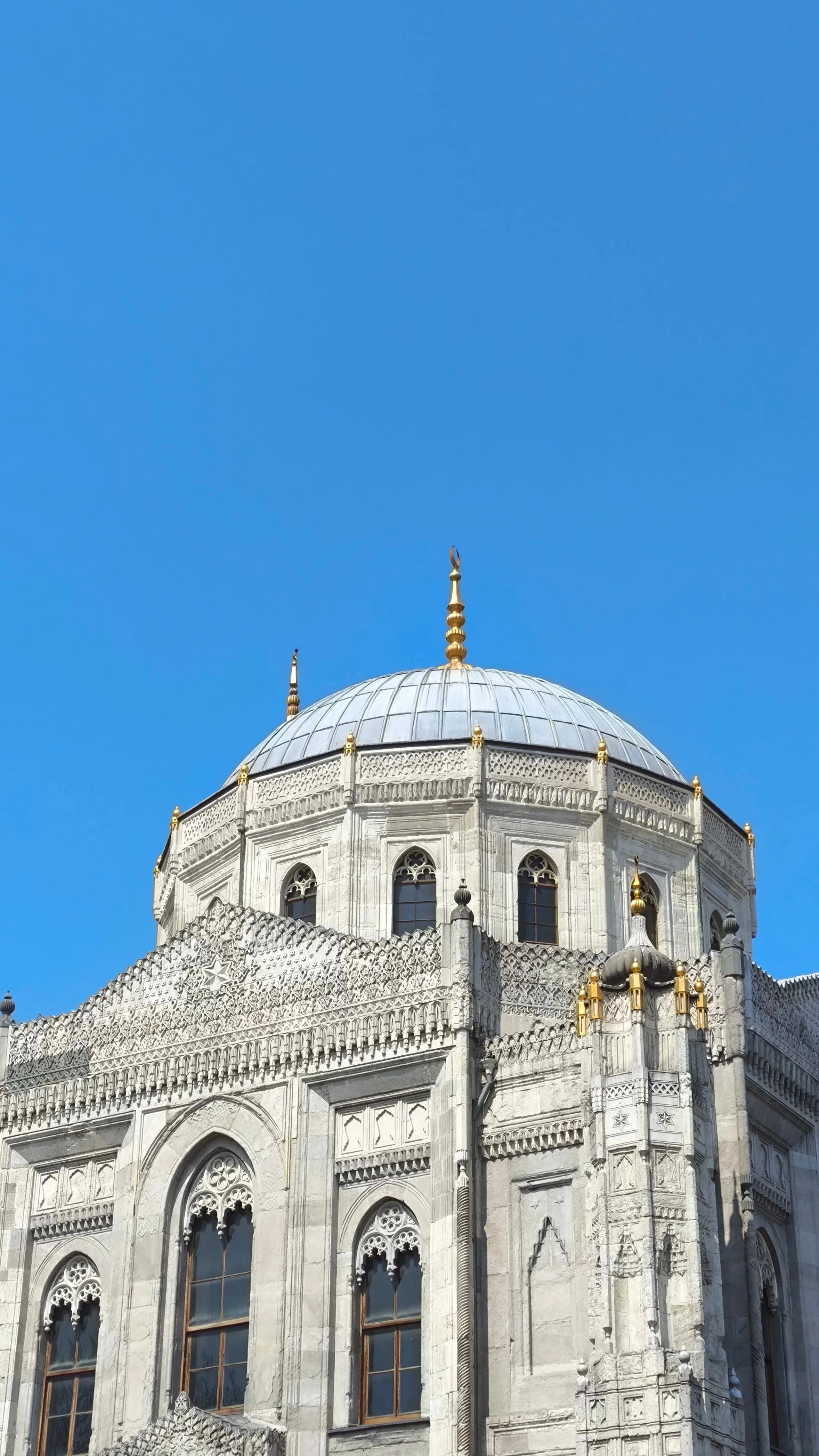 Detailed view of historical Ottoman mosque architecture with a clear blue sky backdrop.
