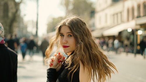 Free Portrait of a young woman with wavy hair and red lips in an urban setting. Stock Photo