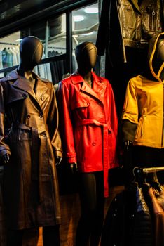 Colorful leather coats on mannequins in a stylish window display.