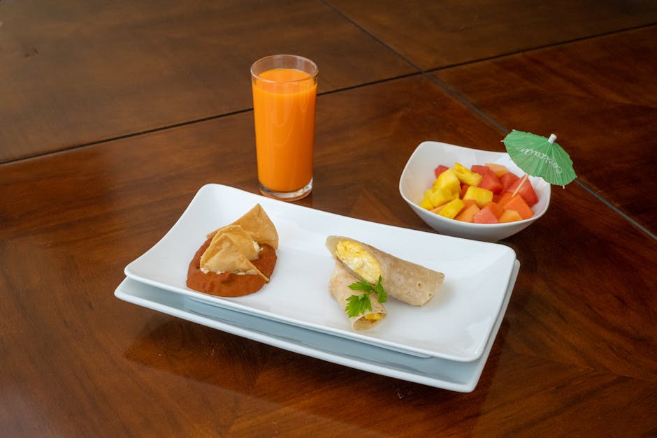Pale yellow-green juice in a tall glass with fresh celery stalks and pineapple wedges arranged next to it.