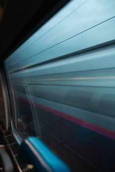Blurred side view of a speeding train scene captured from inside another train.