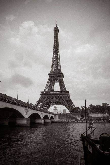 A vintage view of the Eiffel Tower by the river in Paris, France, in black and white.