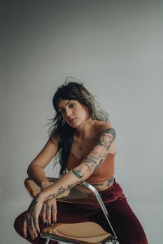 Portrait of a woman with tattoos sitting in a chair, expressing creativity and individuality.