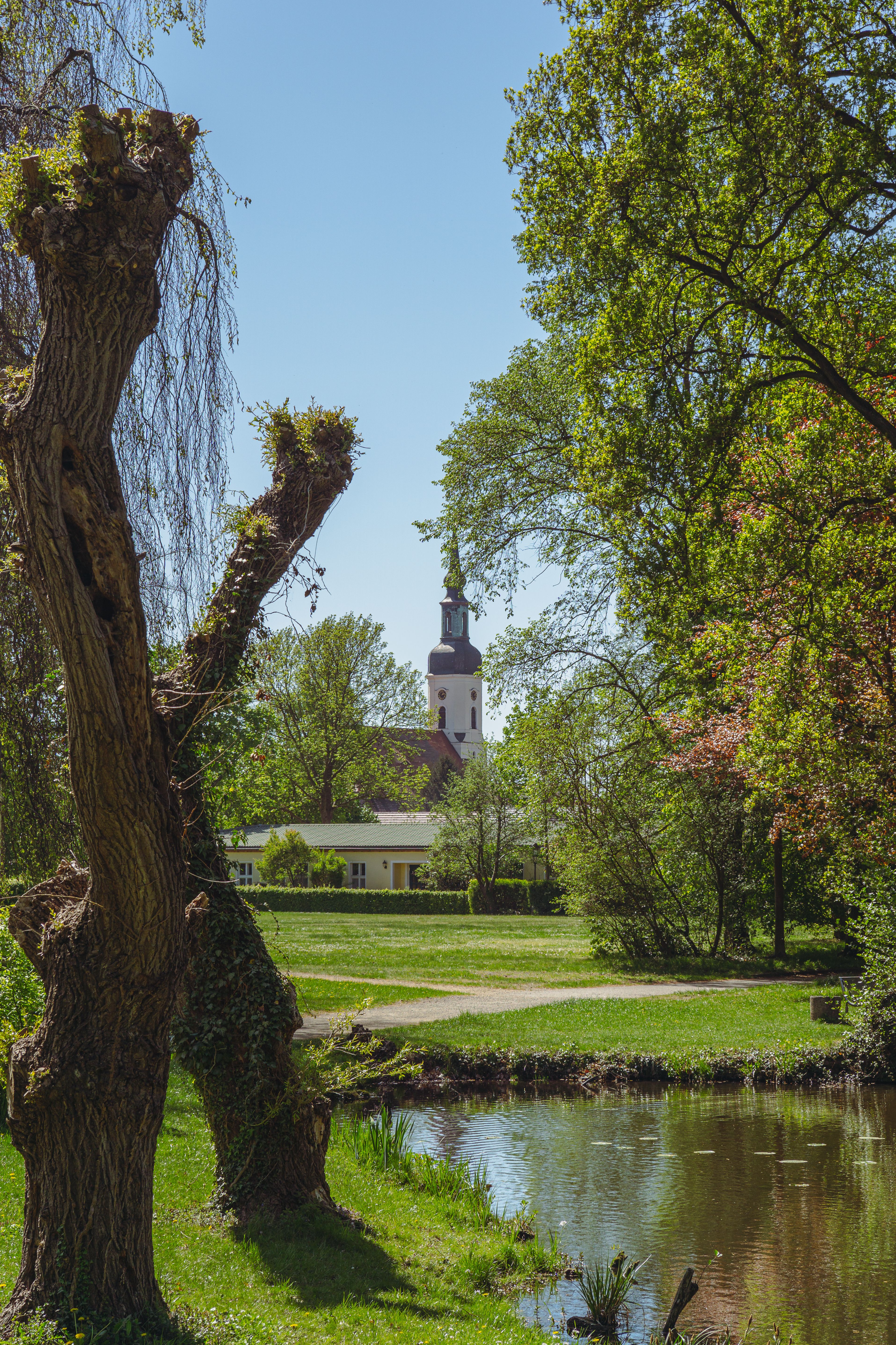 Beautiful spring landscape featuring a church in Lübbenau, surrounded by lush greenery.