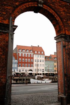 Charming Nyhavn canal scene viewed through a historic arch in Copenhagen.