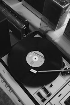 Black and white image of a vinyl record playing on an antique turntable, evoking a vintage aesthetic.