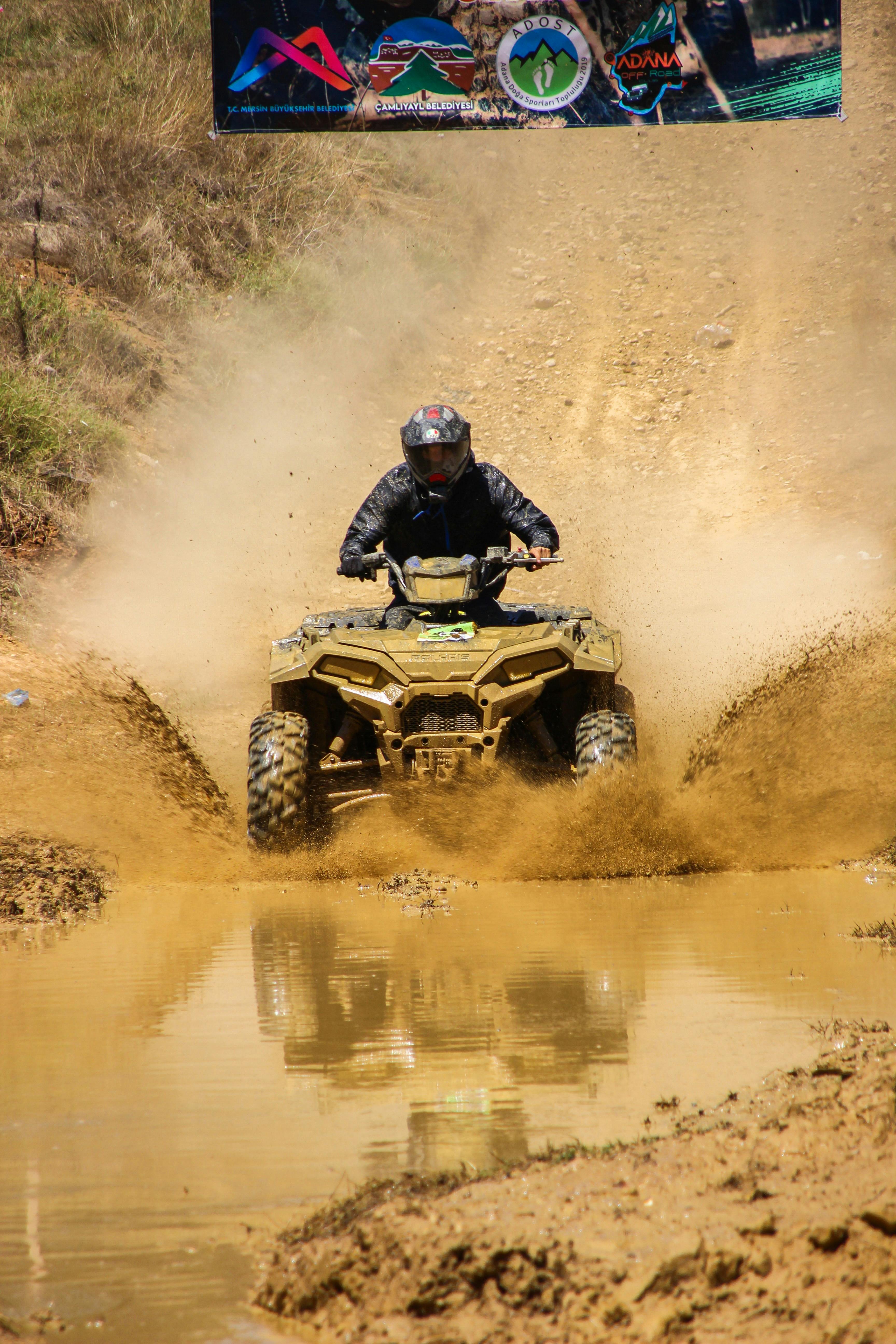 Exciting off-road adventure featuring an ATV rider splashing through muddy water.