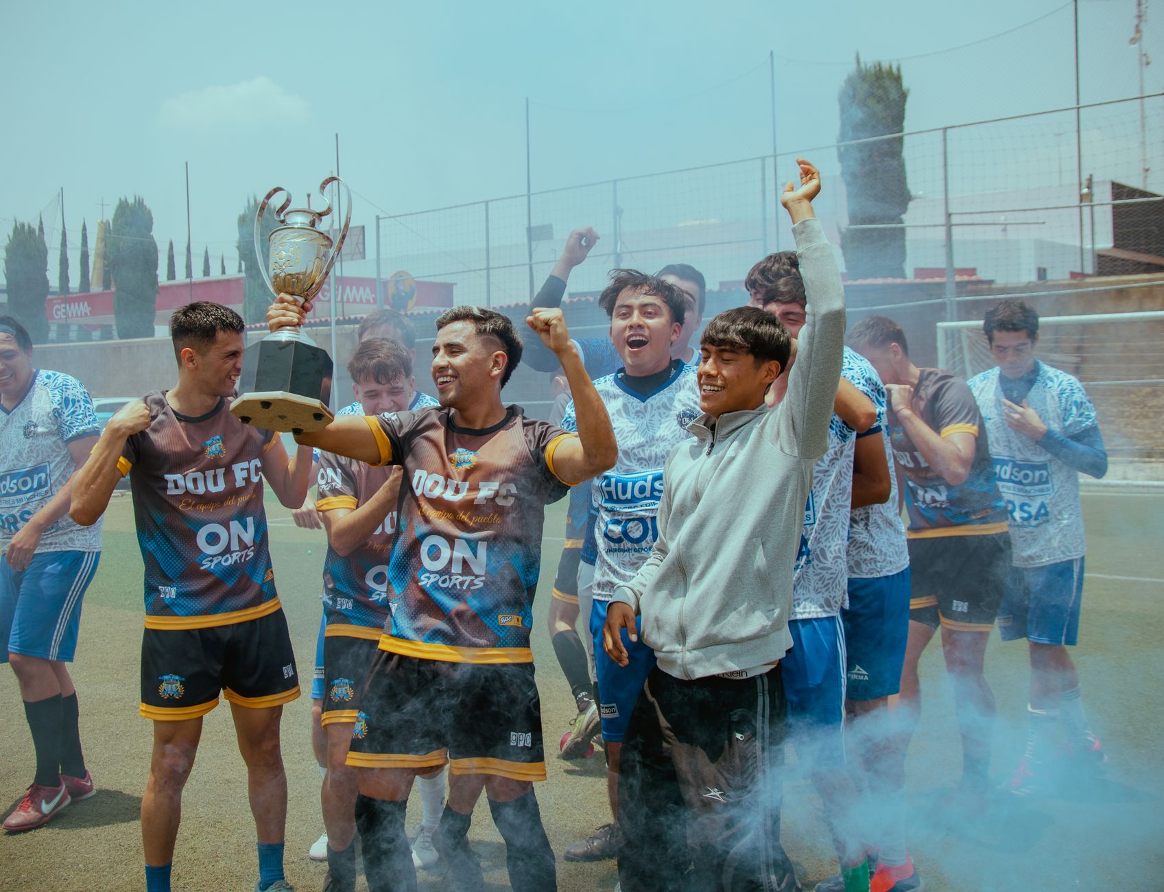 A joyful soccer team celebrates their tournament victory holding a trophy on the field.