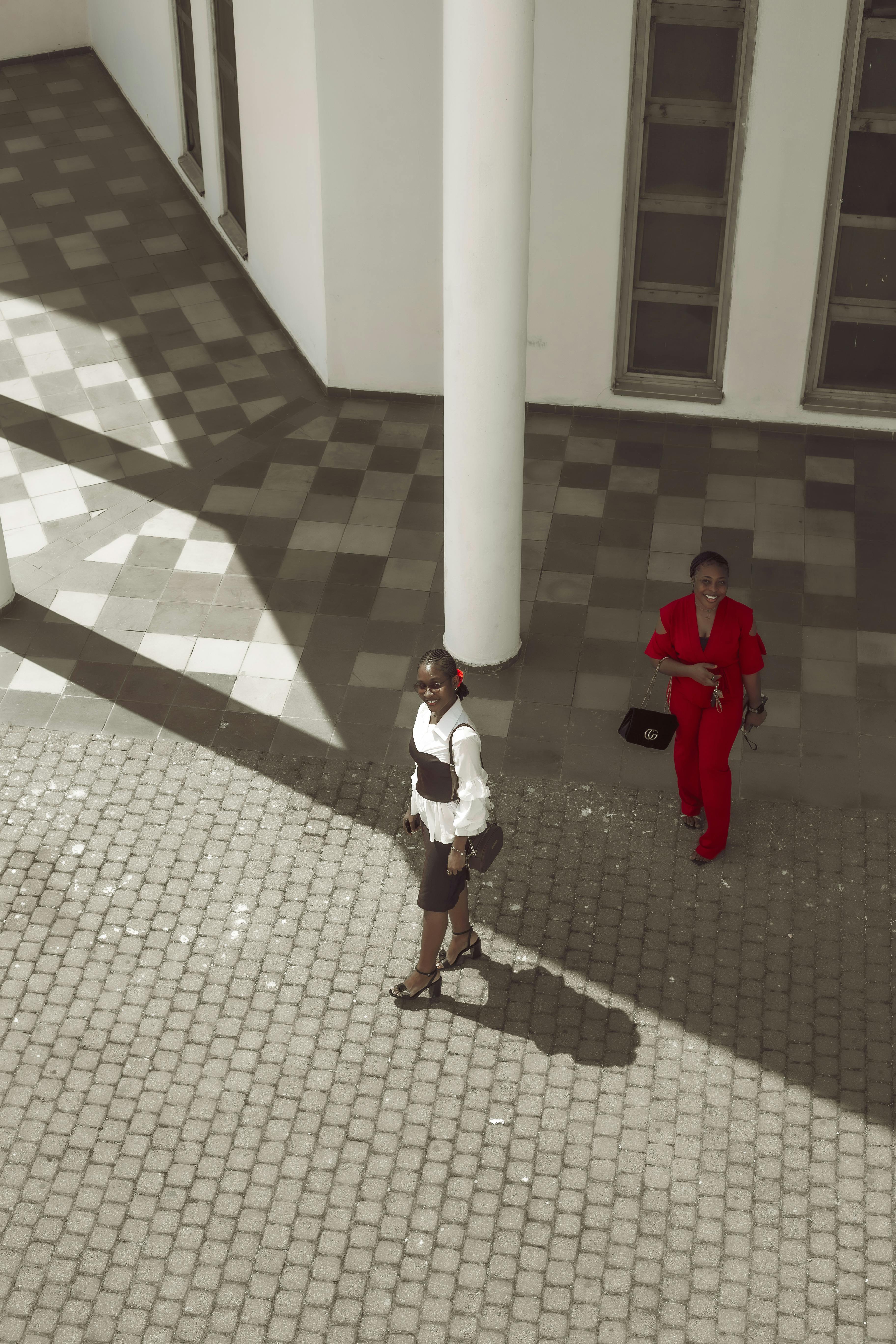 Ücretsiz Geometrik desenli bir kaldırımda şık kıyafetlerle yürüyen iki kadının havadan görünümü. Stok Fotoğraflar