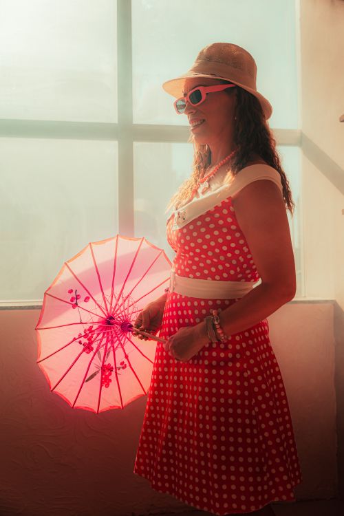 Free Woman in a vintage polka dot dress holding a pink parasol, exuding a retro summer vibe. Stock Photo