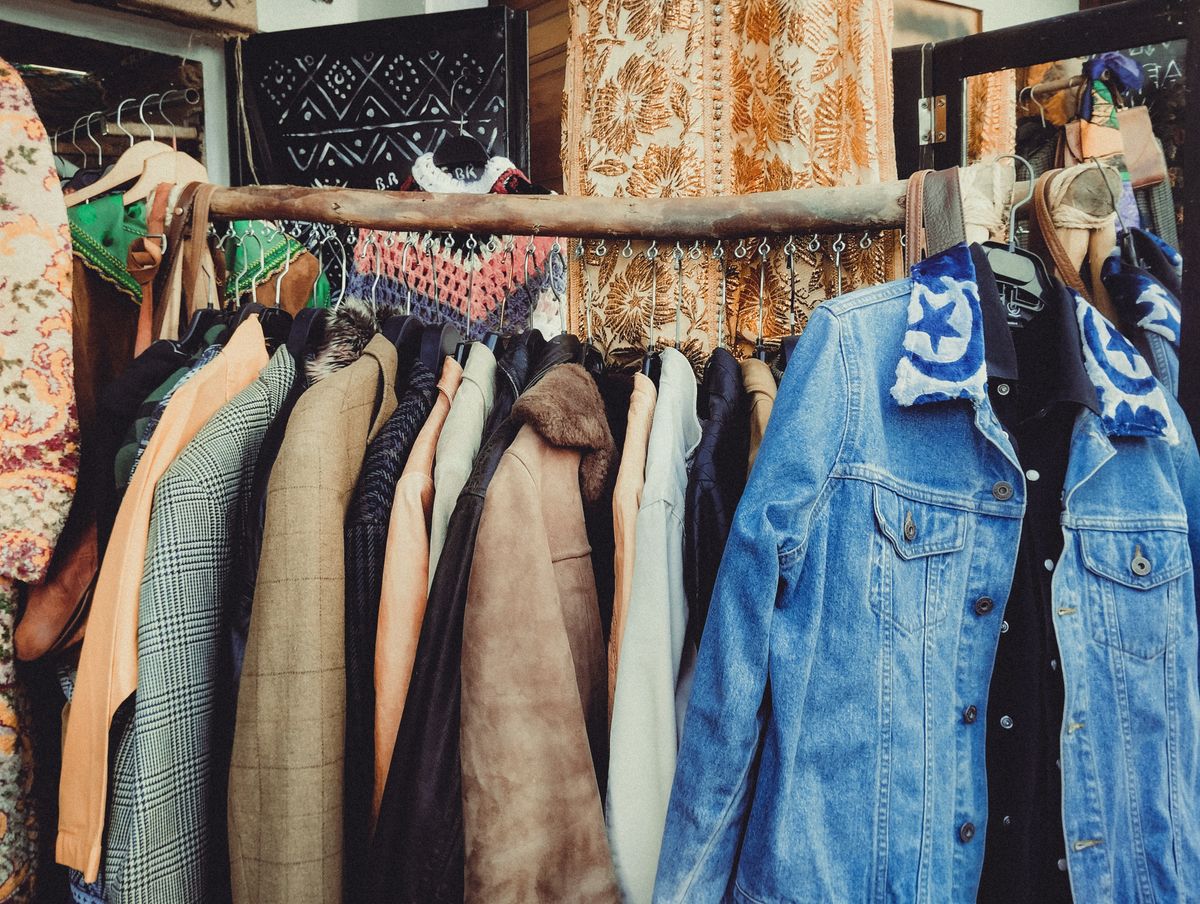 Worn jackets hung close together on a wooden rack