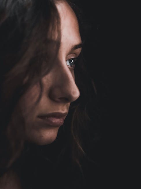 Moody side portrait of a woman looking away, capturing introspection and emotion.