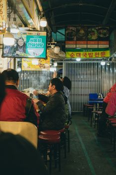 Lively scene of people enjoying street food at a bustling market in Seoul, South Korea.
