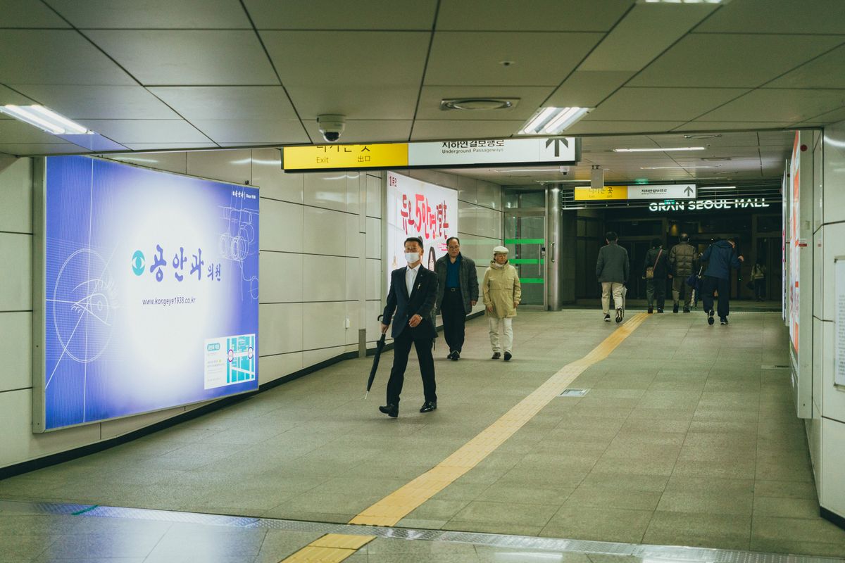 Commuters walk through a Seoul subway station corridor.