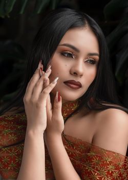 Captivating portrait of a woman in traditional attire with intricate makeup and long hair.