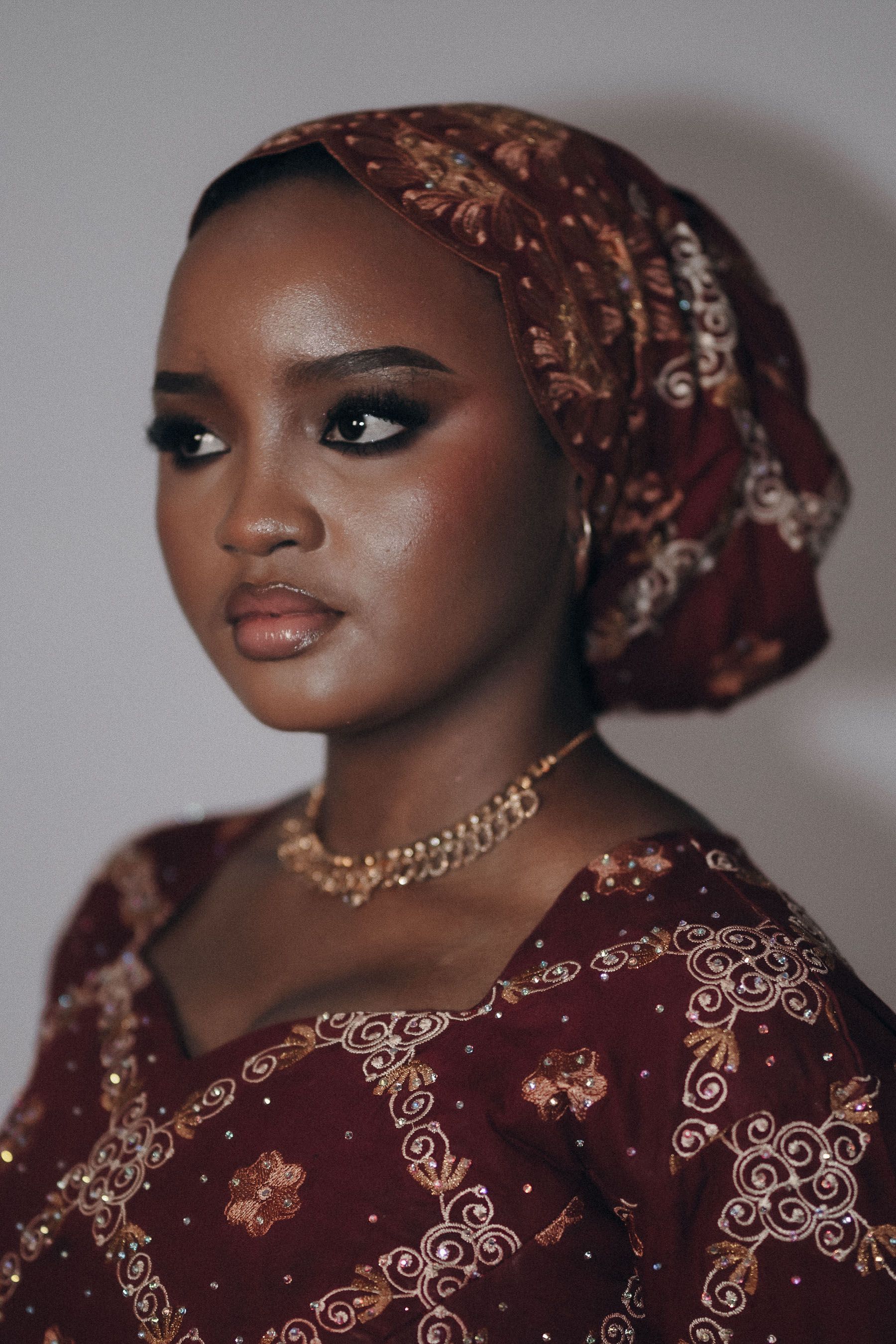 Beautiful portrait of a woman wearing traditional Nigerian attire with a regal expression and intricate embroidery.