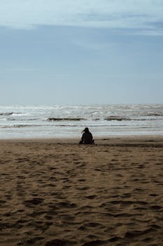 A peaceful view of a person sitting on a sandy beach in Mar del Plata, Argentina.
