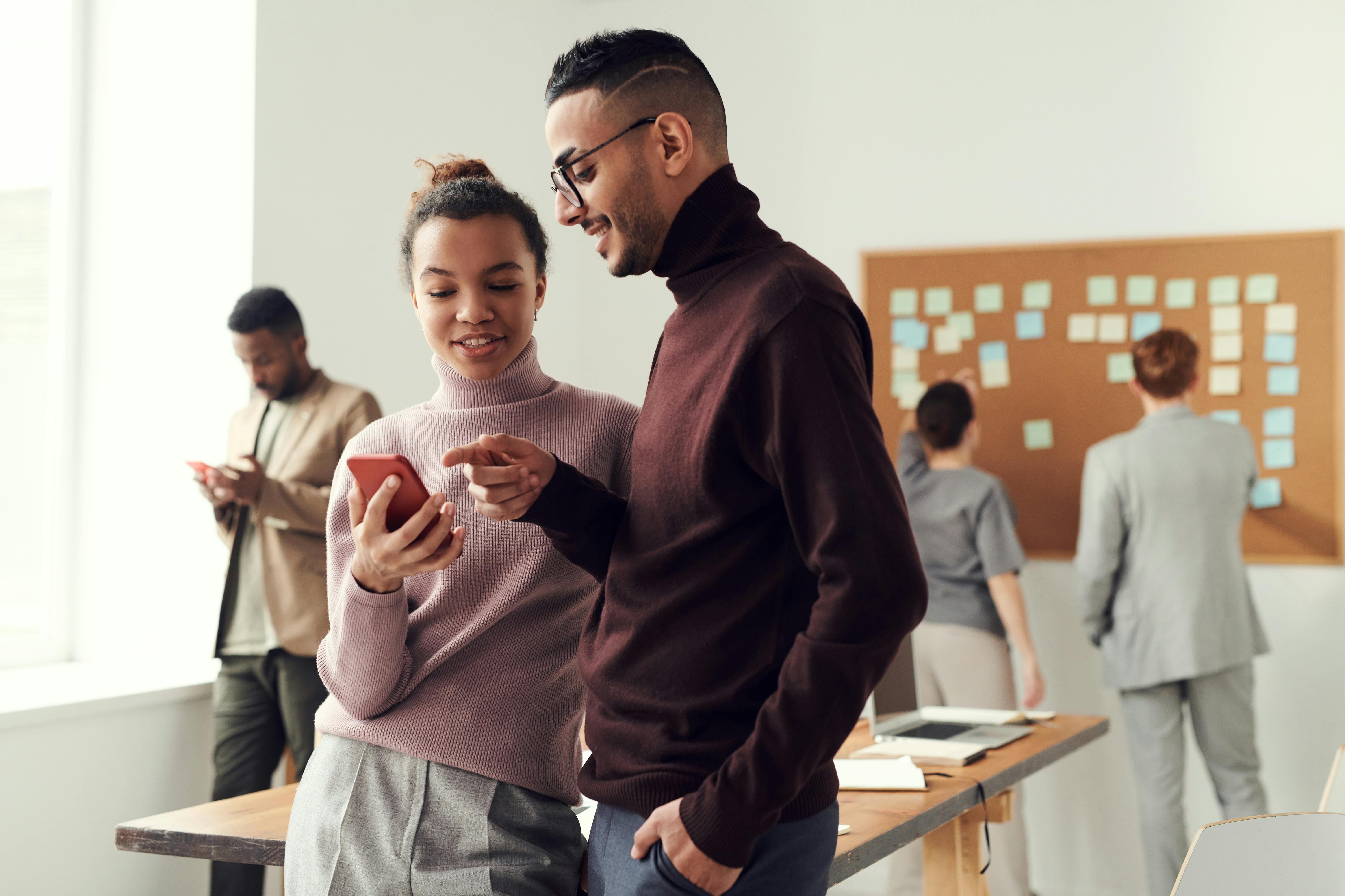 Colleagues collaborating in a contemporary office while viewing content on a smartphone.