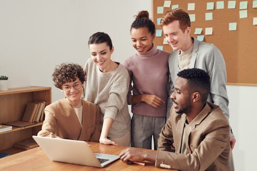 Group of diverse professionals engaged in brainstorming session around a laptop indoors.