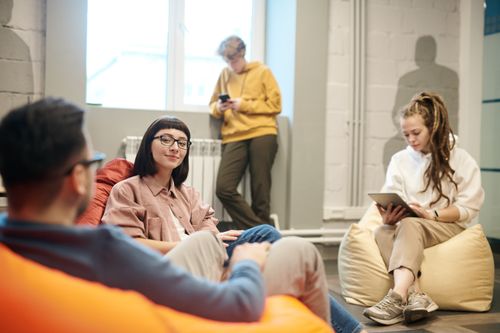 Free Young adults relaxing indoors with mobile devices, creating a casual atmosphere. Stock Photo