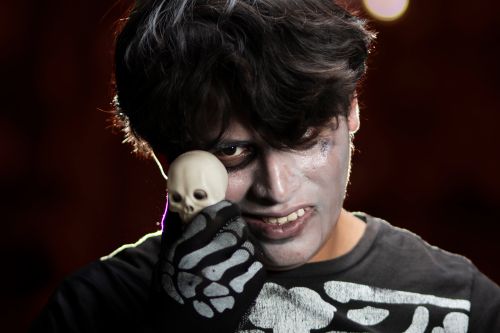 Free A person in skeleton makeup holding a small skull, perfect for Halloween themes. Stock Photo