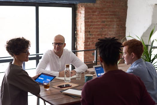 Diverse team collaborating in a modern office setting with laptops and notes on the table.