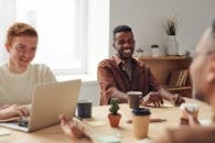 在明亮的现代化办公室里，一群不同的专业人士围着一张木桌举行休闲团队会议