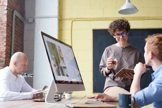 Diverse team having a discussion in a modern office setting with computers.