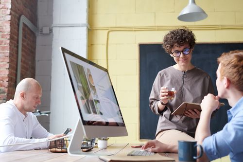 Free Diverse team having a discussion in a modern office setting with computers. Stock Photo