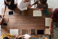 一群成年人围着一张装有科技设备的木桌，正在开会讨论计划