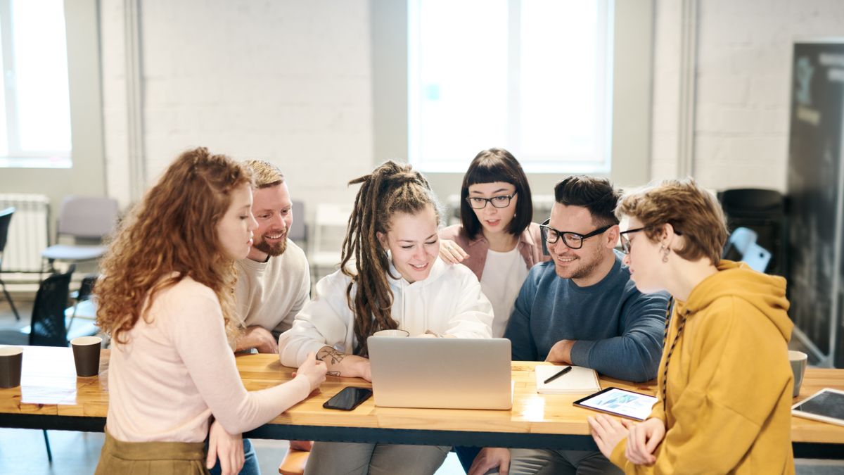 Team collaborating around a laptop to design human-in-the-loop AI UX