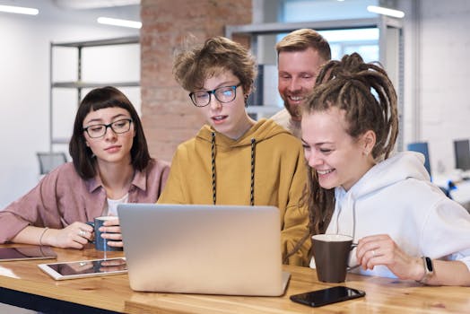 Young professionals in a vibrant office brainstorming on laptops and enjoying coffee.