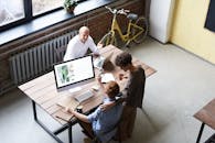 三名同事在时尚的办公环境中，正围着电脑热情地讨论项目