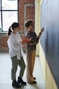Two Women Standing Near Chalk Board