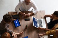 俯视现代工作空间中与笔记本电脑和平板电脑协作的多元化团队