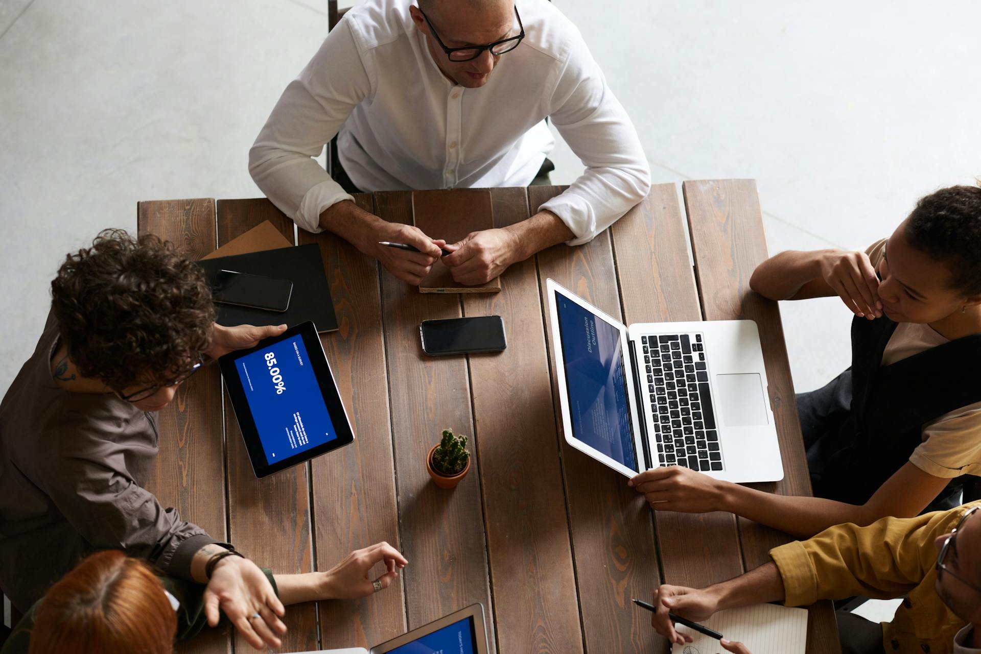 Top view of a diverse team collaborating with laptops and tablets in a modern workspace.