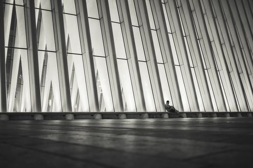Free A lone person sits against a modern architectural facade in New York City at night. Stock Photo