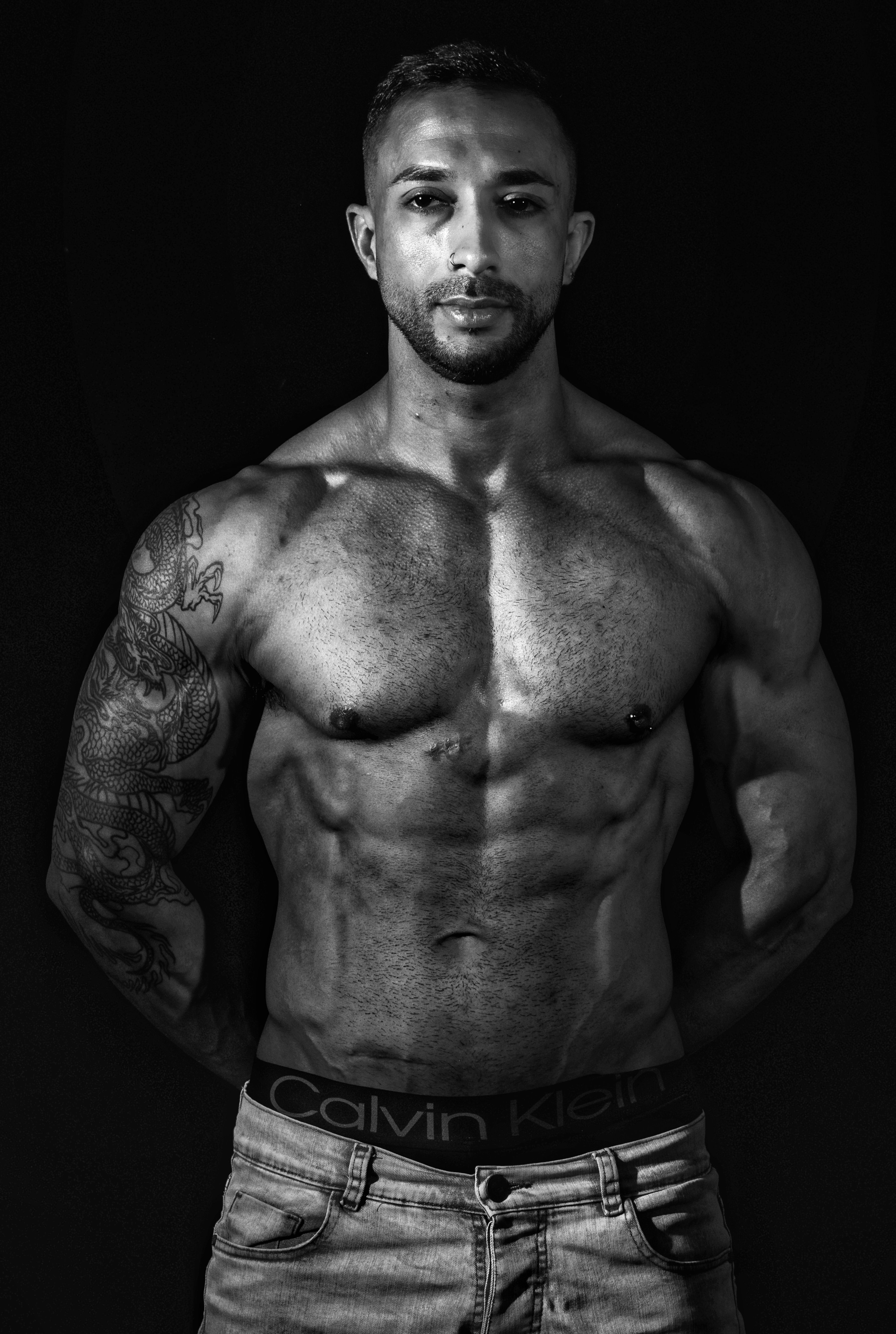 Stunning black and white portrait of a muscular man showcasing tattoos and physique.