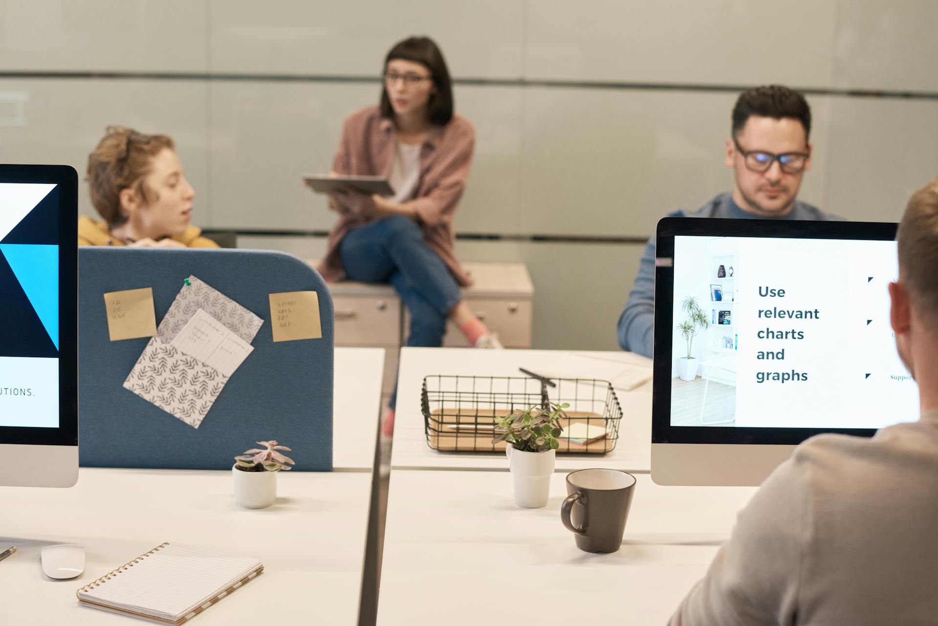 Casual office environment with team collaborating using digital devices and computers for effective project discussions.