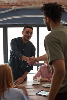 Diverse colleagues engaging in a business meeting indoors, sealing a deal with a handshake.