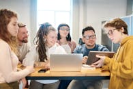 一群多元化的专业人士围着一张带有技术的木桌进行头脑风暴