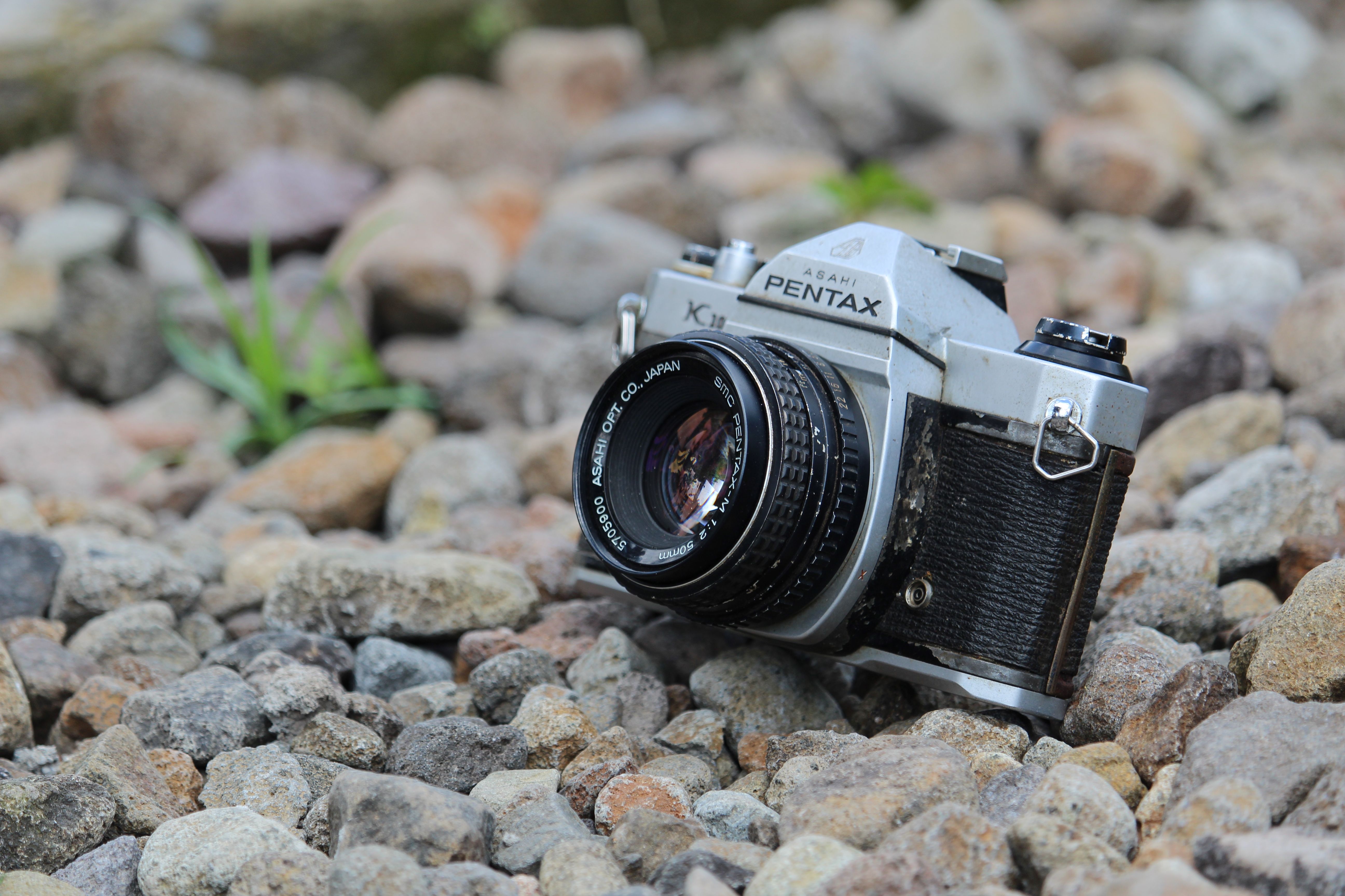 A vintage Pentax Asahi camera placed on a bed of stones, showcasing its classic design.