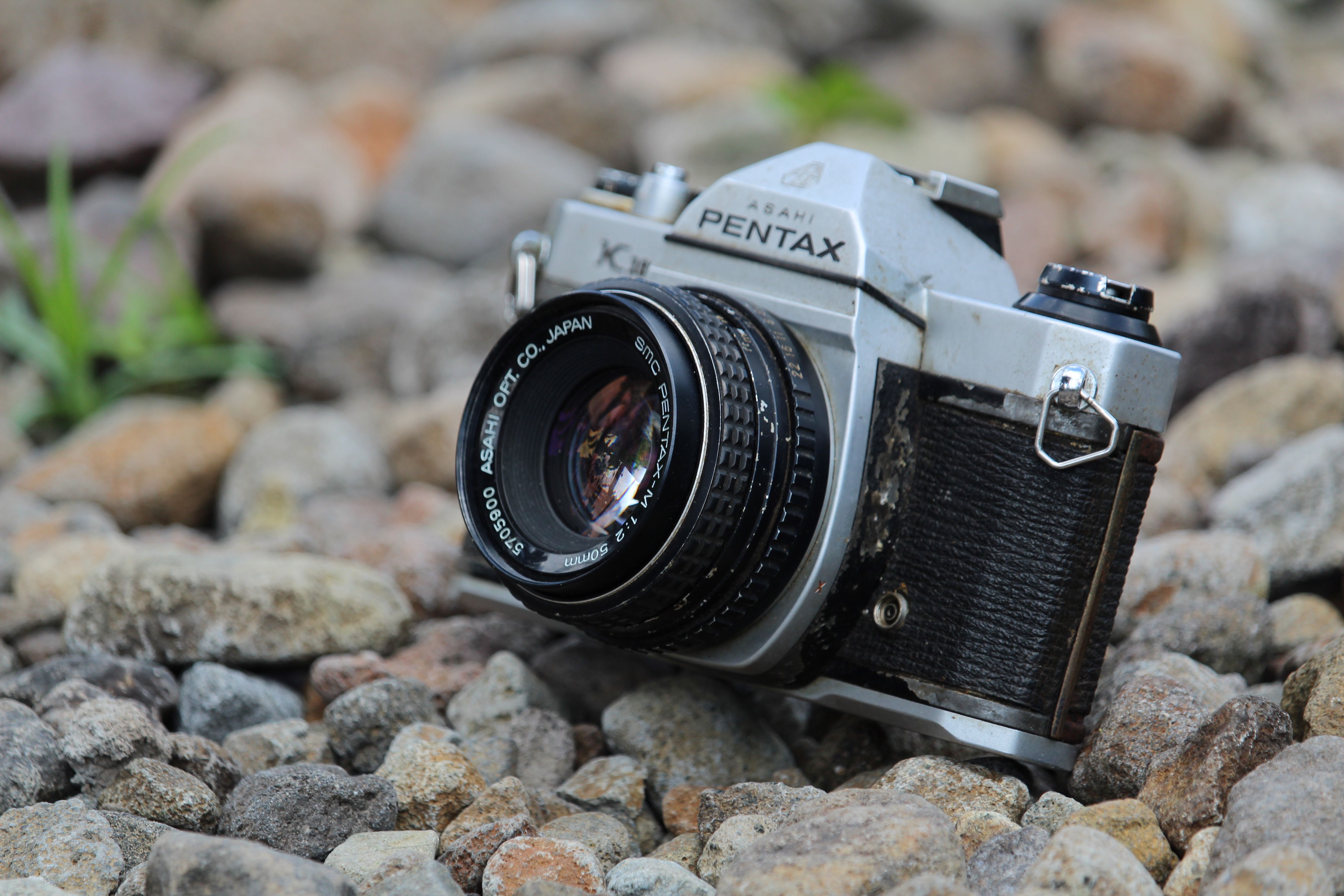 A classic Pentax Asahi film camera resting on rocky terrain, showcasing vintage technology.