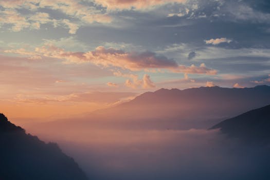 Majestic view of sunrise with mist enveloping mountain valleys, creating a serene and tranquil scene.