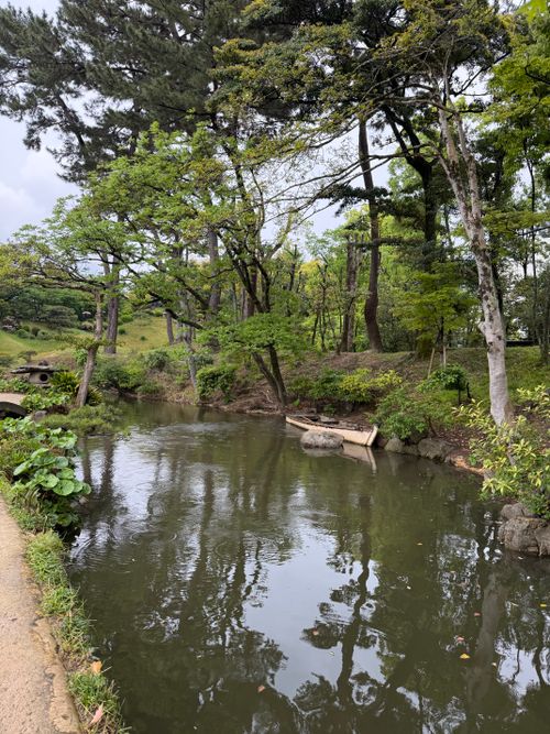 Free Tranquil pond in a lush Japanese garden, reflecting surrounding greenery and trees. Stock Photo
