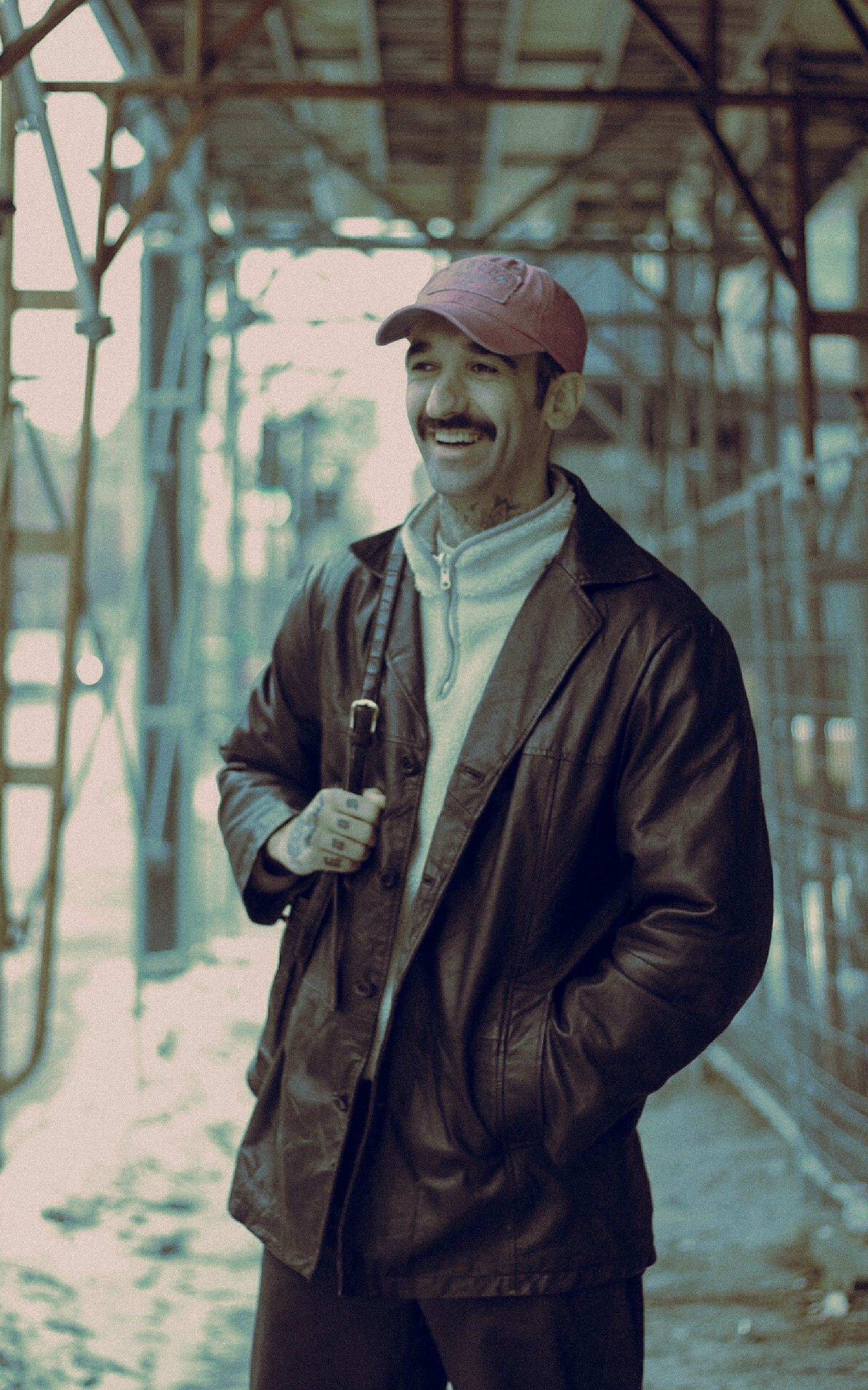 Casually dressed man with mustache and pink cap under scaffolding in Montreal.