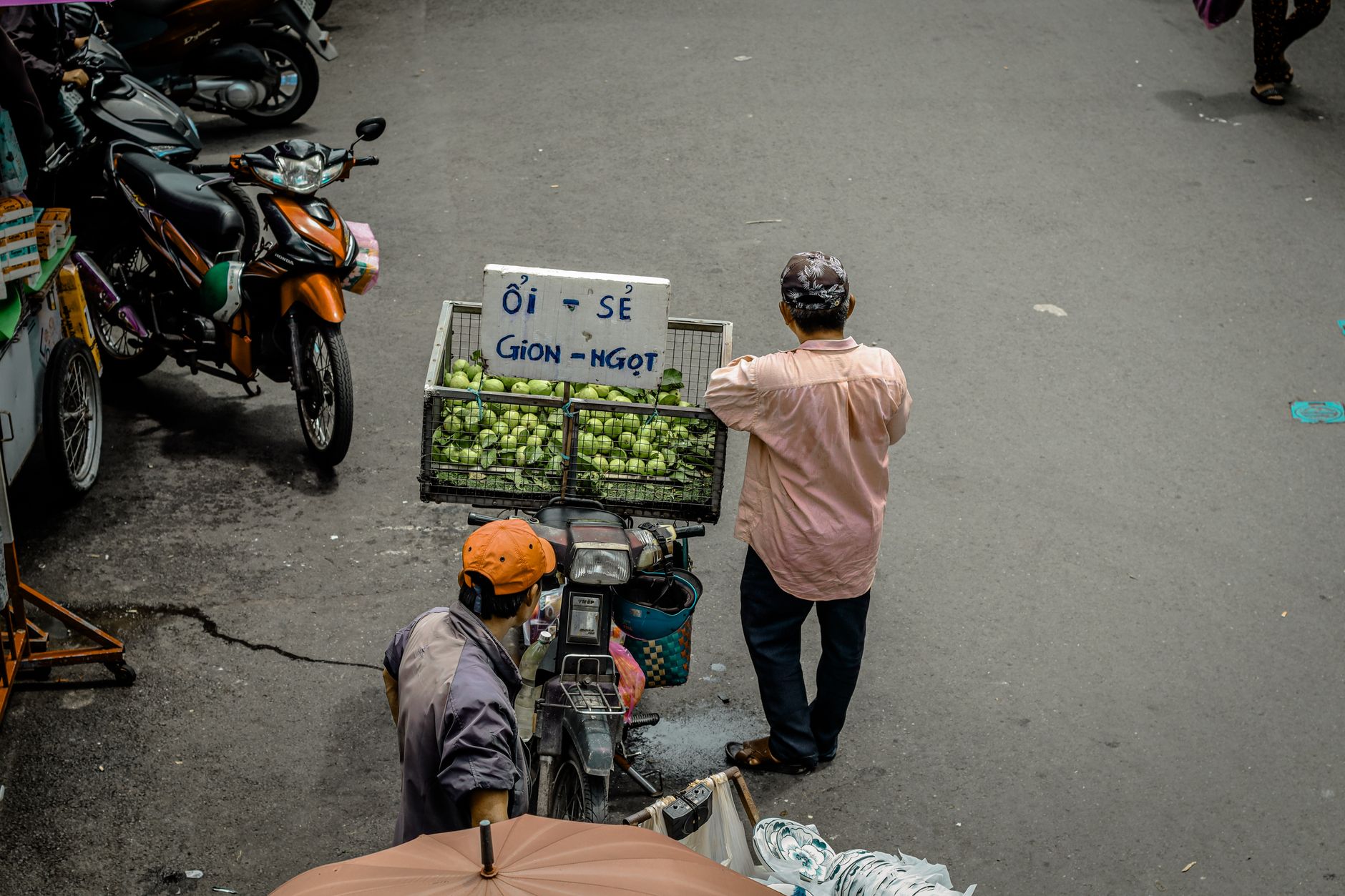Street vendor with fresh guavas displayed on a motorbike, captured in a busy urban setting.