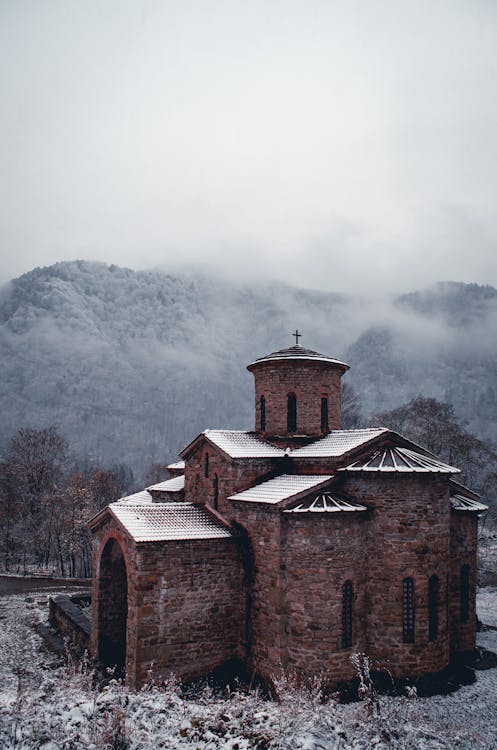 Free Brown Brick Church Near Mountains In Winter  Stock Photo