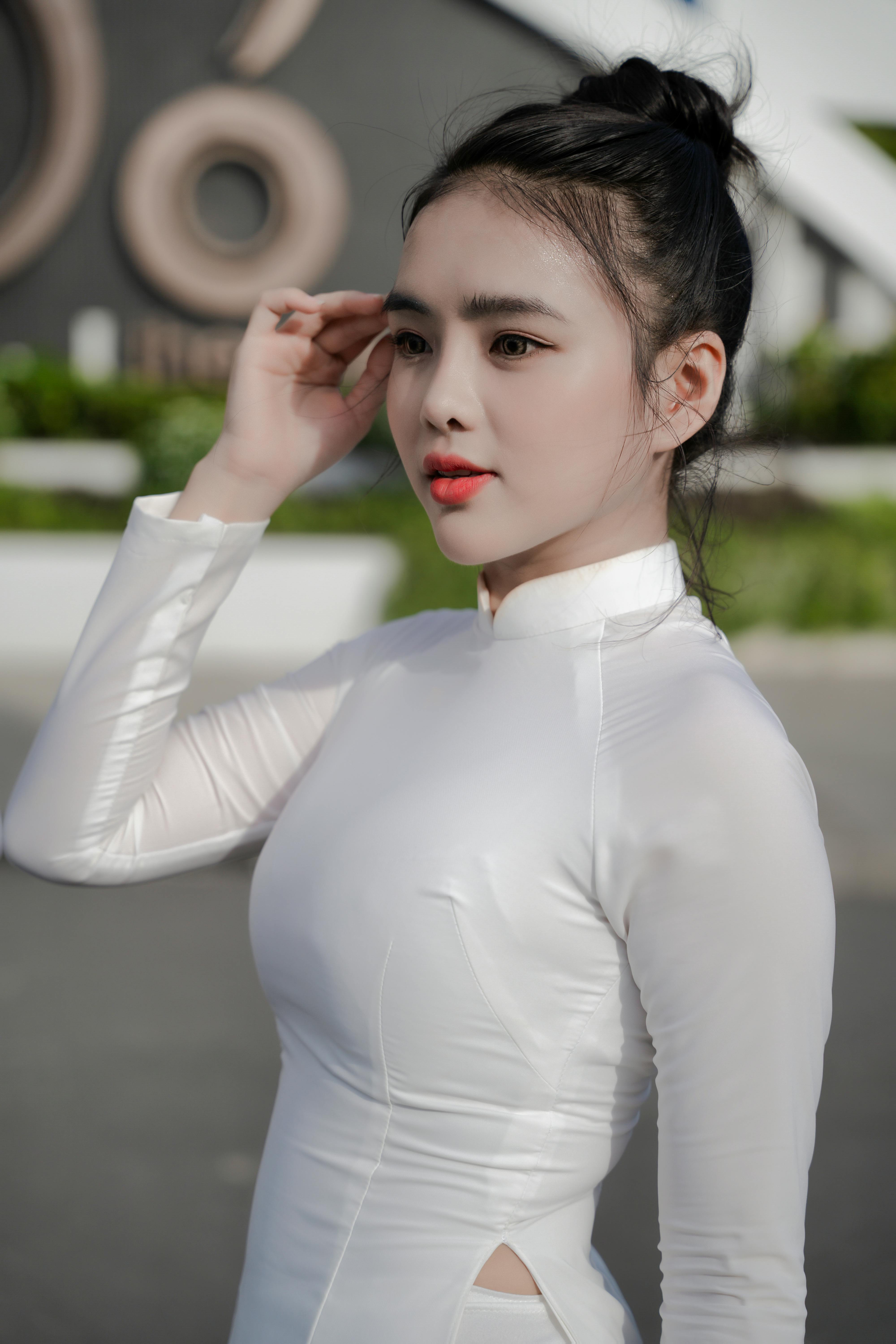 Portrait of a woman in a white Ao Dai dress, gracefully posing outdoors.