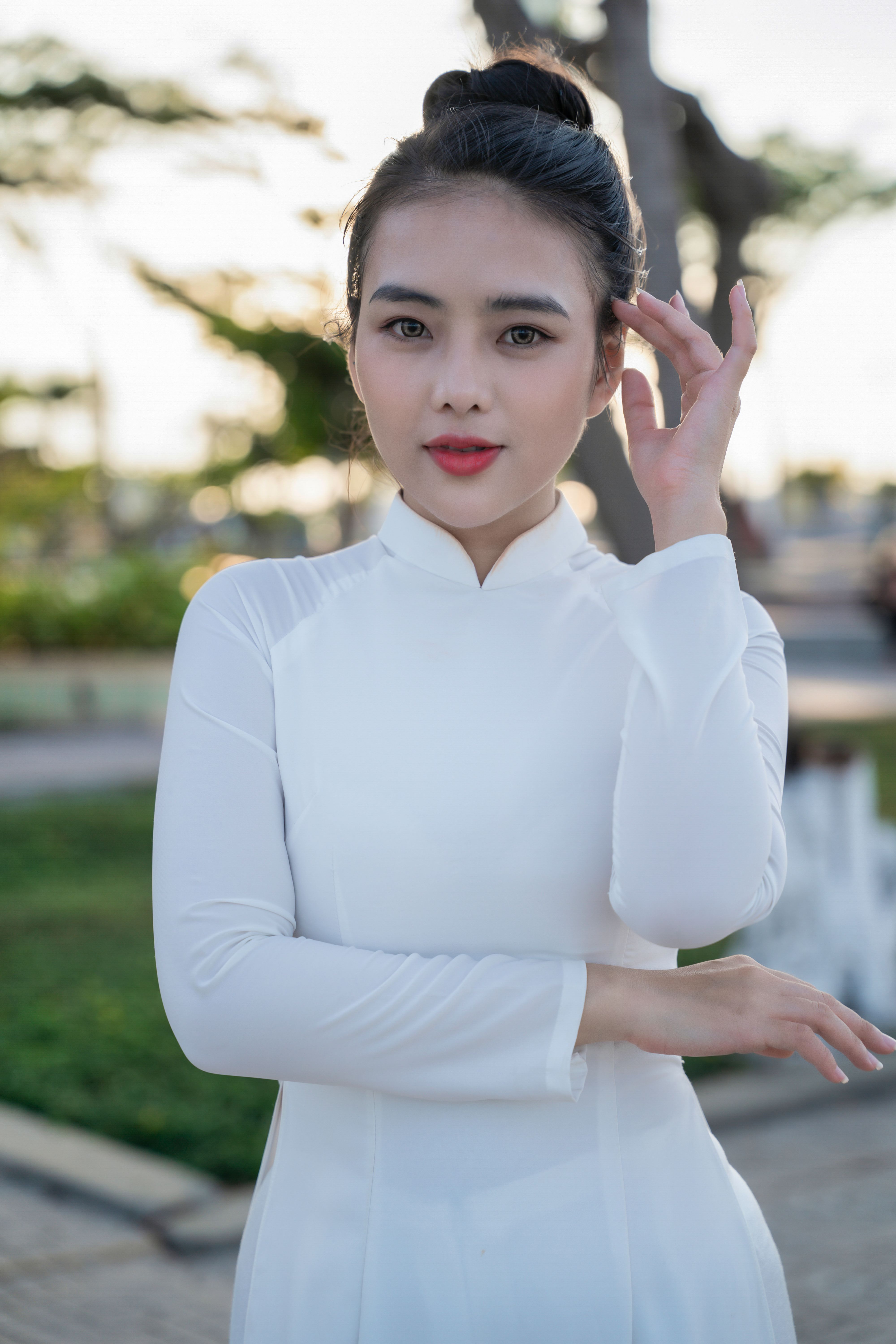 Portrait of a woman in a white Ao Dai standing outdoors, exuding grace and elegance.